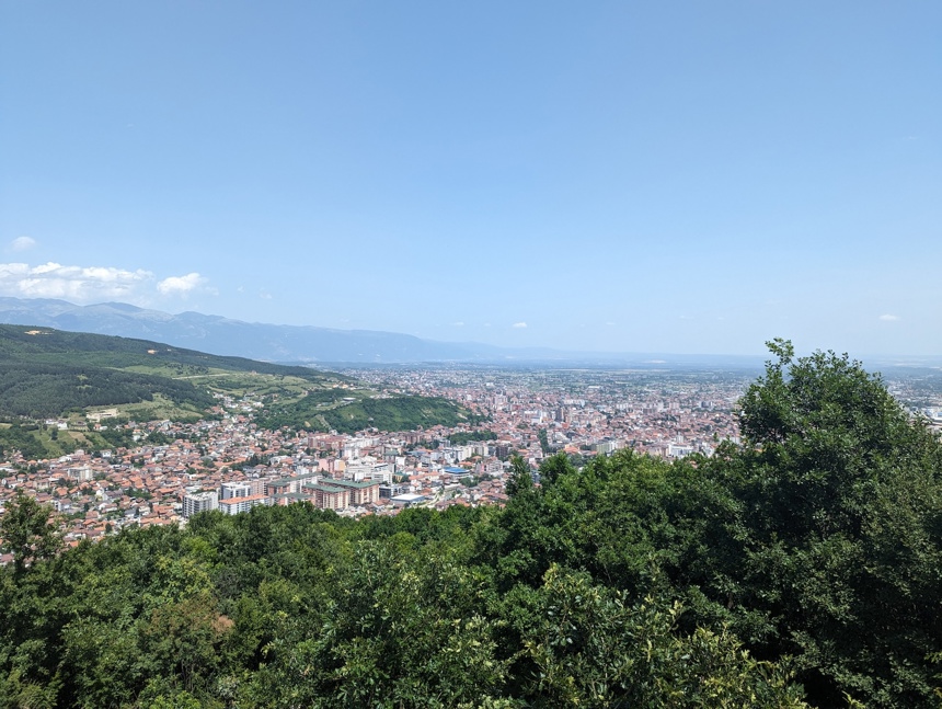 A scenic shot of Peja and its buildings amongst the fields and trees that surround it