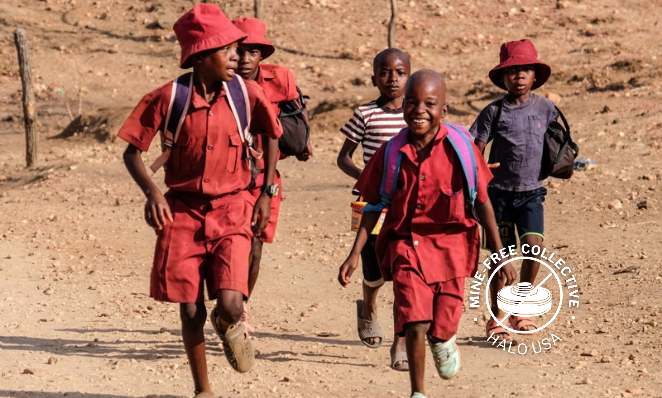 Children run down in a sandy field. The Mine Free Collective logo is in the corner.