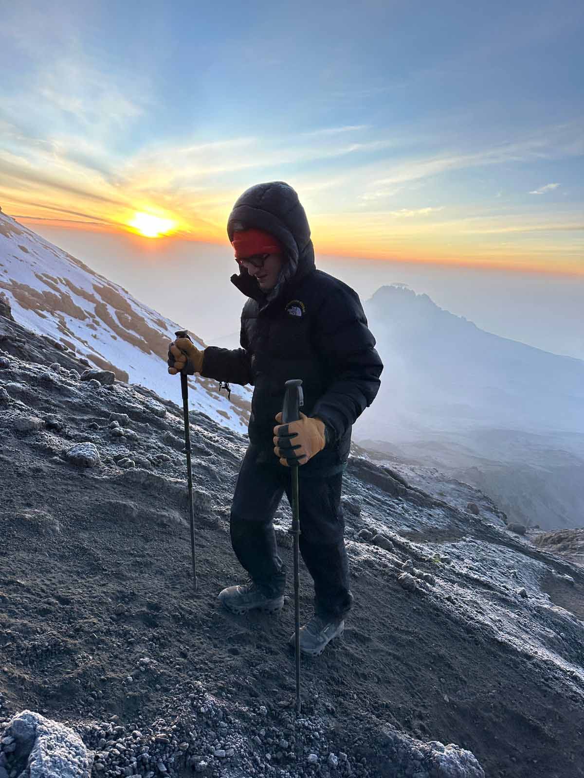 Man with trekking poles climbing Mount Kilimanjaro