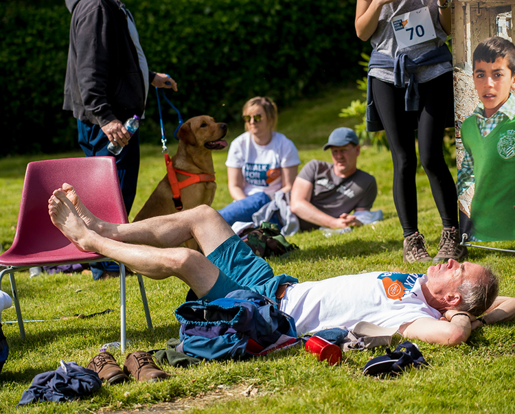 People lay on the grass with water bottles as they rest after their 30km walk for Syria