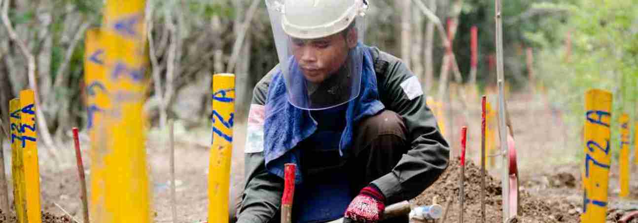 A manual deminer wears PPE and works on marked mines in Cambodia