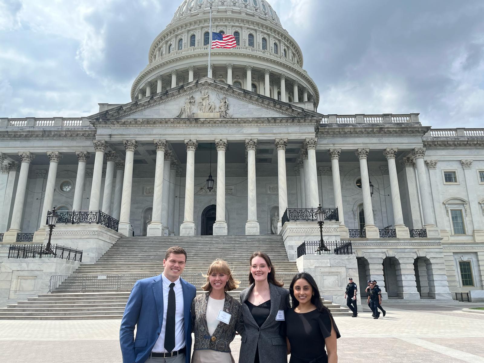 Four student advocates stand in front of the Capitol building.