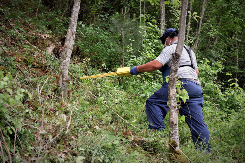 Battle area clearance deminer, uses a Schonstedt Magnetic Locator in a forest