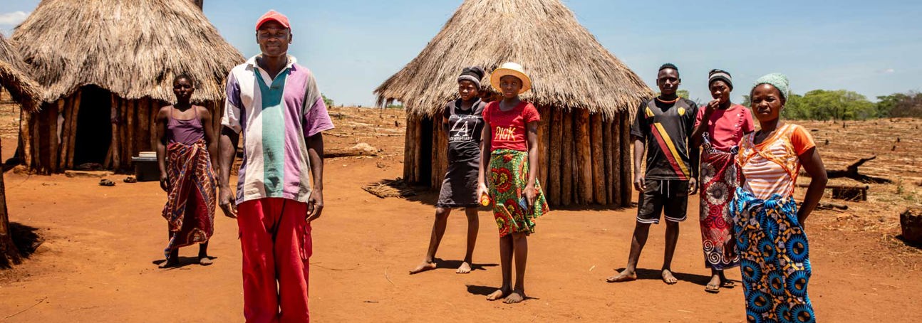 A group of Zimbabwean villagers stand on the ground outside their houses