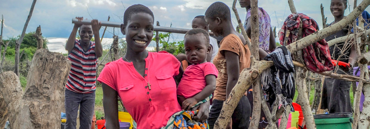 A woman and her son collect water from a borehole on ground made safe by HALO