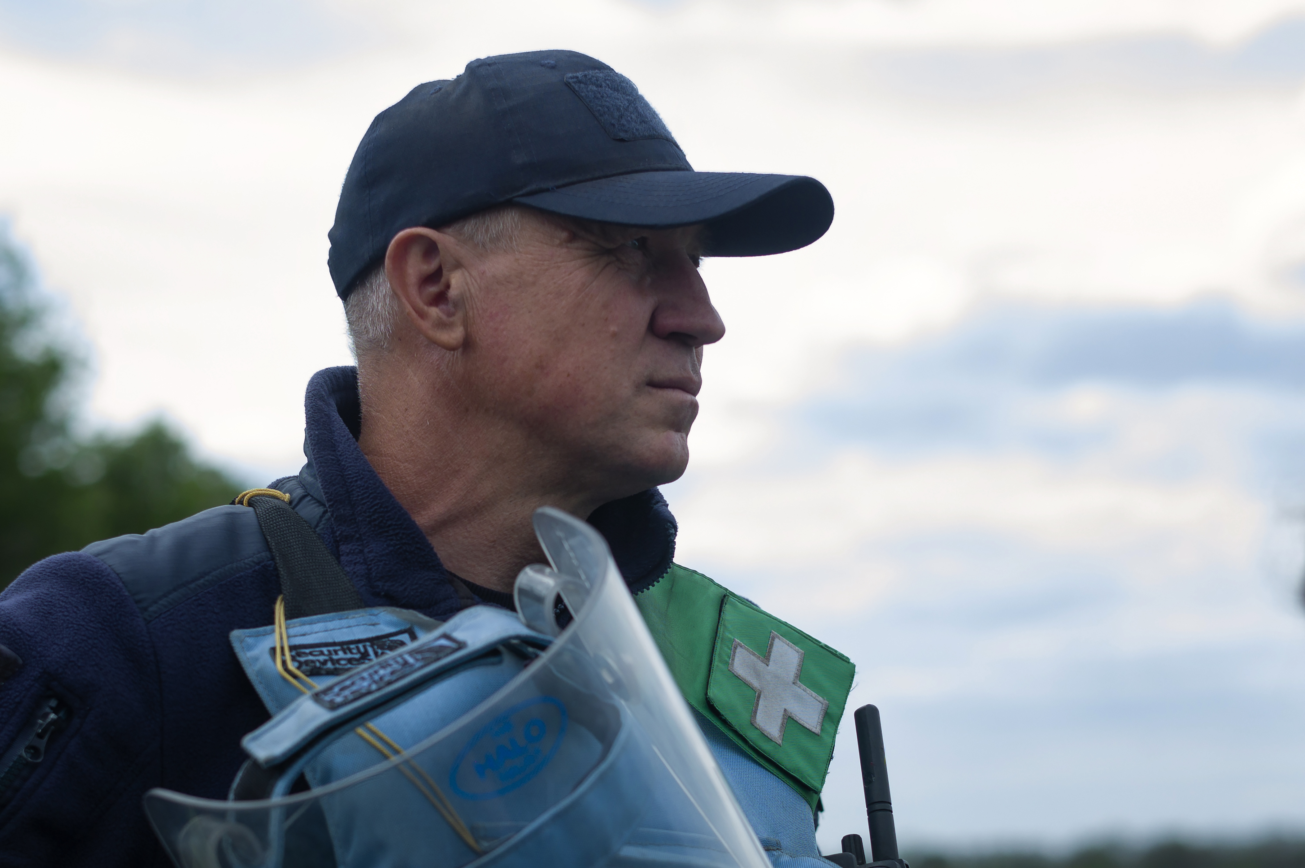 A deminer wearing PPE looks into the distance outside