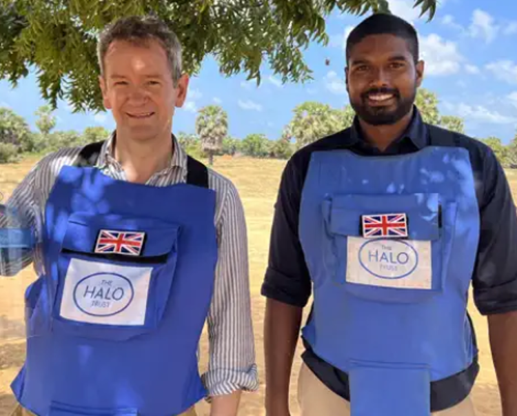 Two HALO staff members stand under a tree wearing PPE