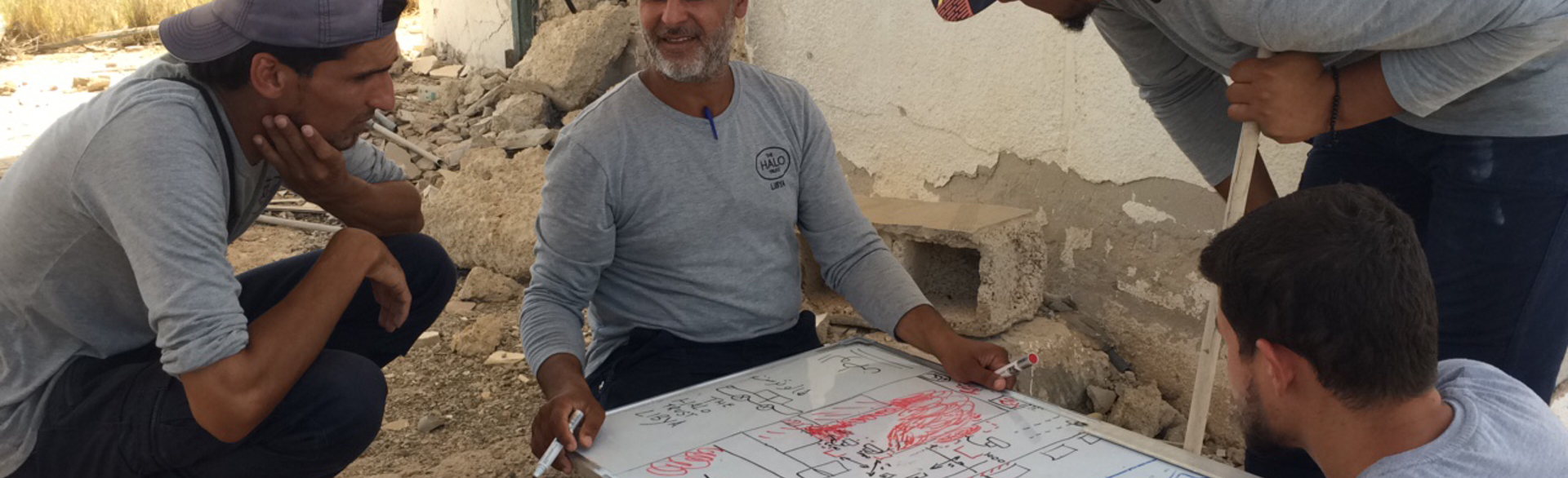 Hussain, HALO's operations manager, sits around a white board with his colleagues